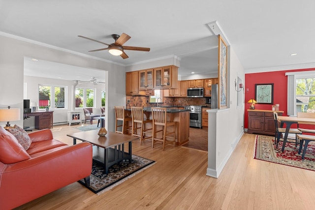 living area with a ceiling fan, light wood-style floors, baseboard heating, baseboards, and recessed lighting