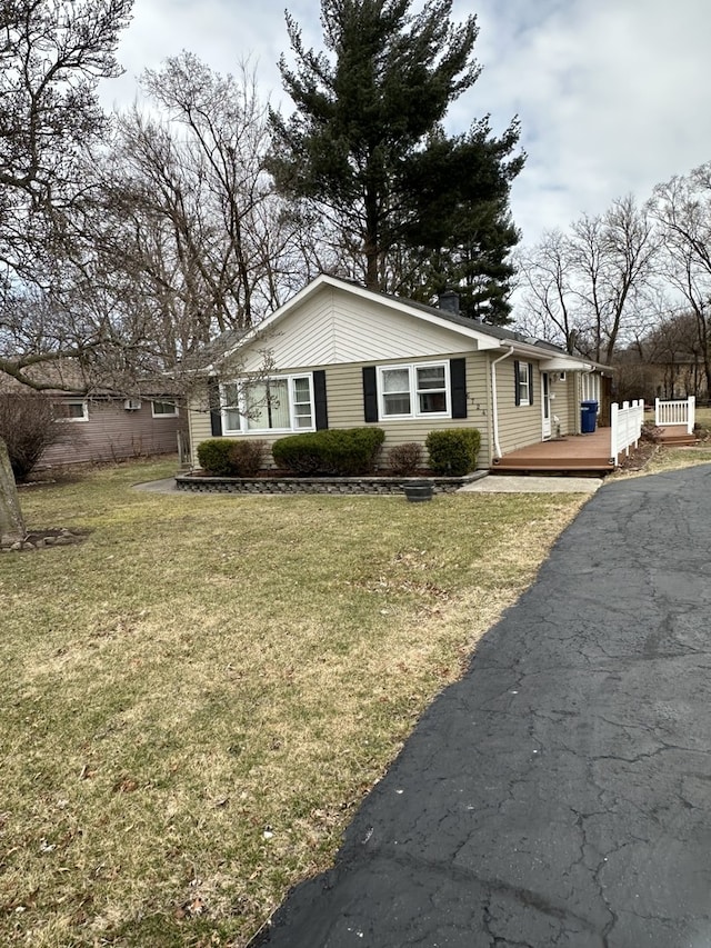 view of home's exterior featuring a lawn, driveway, and a wooden deck