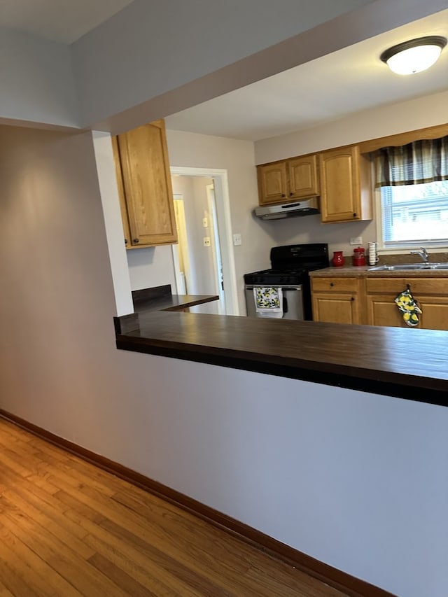 6724 W 114th St, Worth, IL 60482 - kitchen with stainless steel range with gas cooktop, under cabinet range hood, dark countertops, a sink, and wood finished floors