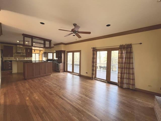 unfurnished living room featuring ornamental molding, baseboards, dark wood-style flooring, and ceiling fan