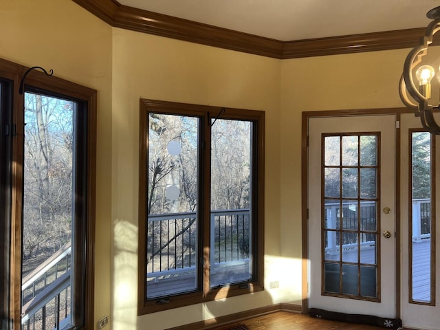 entryway featuring wood finished floors, baseboards, a chandelier, and crown molding