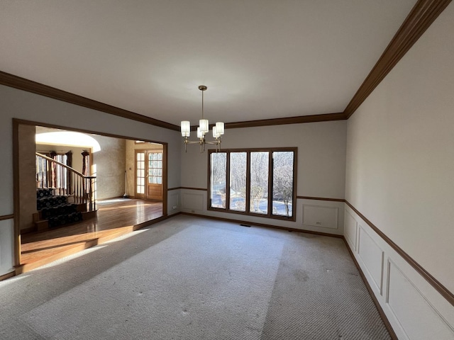 unfurnished room featuring light carpet, a notable chandelier, stairs, and a wainscoted wall