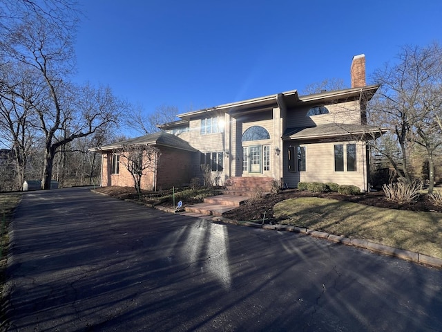 view of front of home featuring driveway and a chimney