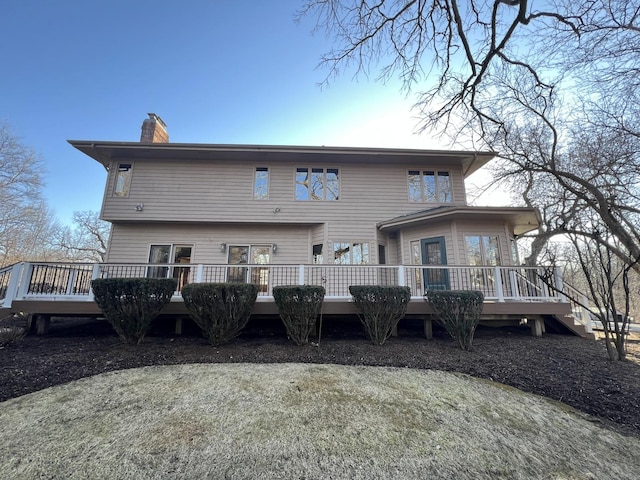 back of house with a wooden deck and a chimney