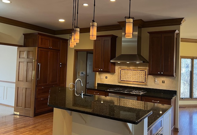 kitchen featuring stainless steel gas cooktop, ornamental molding, a sink, wall chimney range hood, and light wood-type flooring