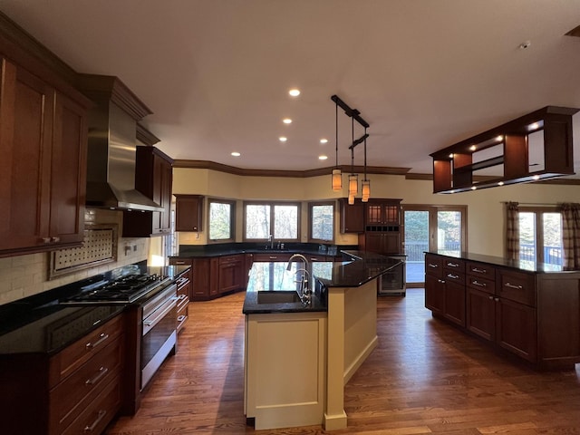 kitchen with tasteful backsplash, a sink, extractor fan, a center island with sink, and dark wood-style flooring