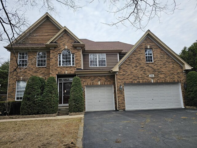 view of front of property with brick siding, an attached garage, driveway, and a shingled roof