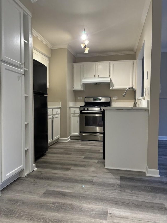 kitchen with freestanding refrigerator, under cabinet range hood, stainless steel range with gas cooktop, and ornamental molding