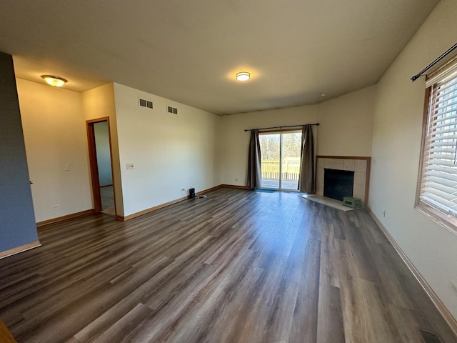 unfurnished living room with dark wood-style floors, visible vents, and baseboards