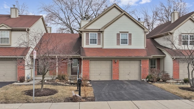 traditional-style home featuring a garage, brick siding, and aphalt driveway