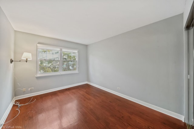 spare room featuring dark wood-style floors and baseboards