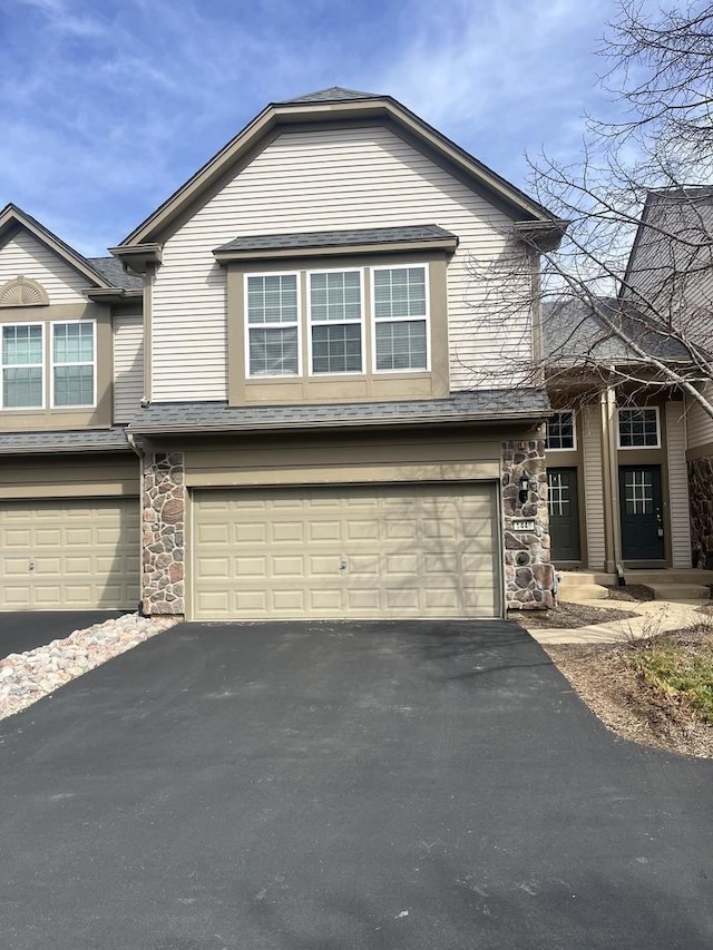 view of front of home featuring driveway, a garage, and stone siding