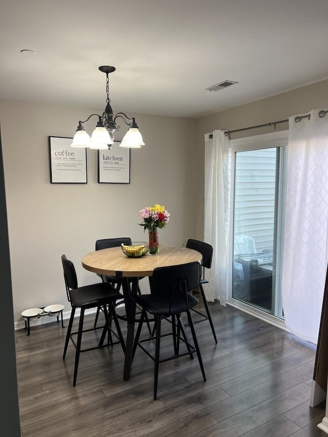 dining area featuring dark wood finished floors, a notable chandelier, and visible vents