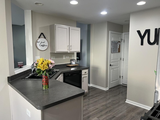 kitchen featuring black dishwasher, dark wood finished floors, a sink, dark countertops, and white cabinets