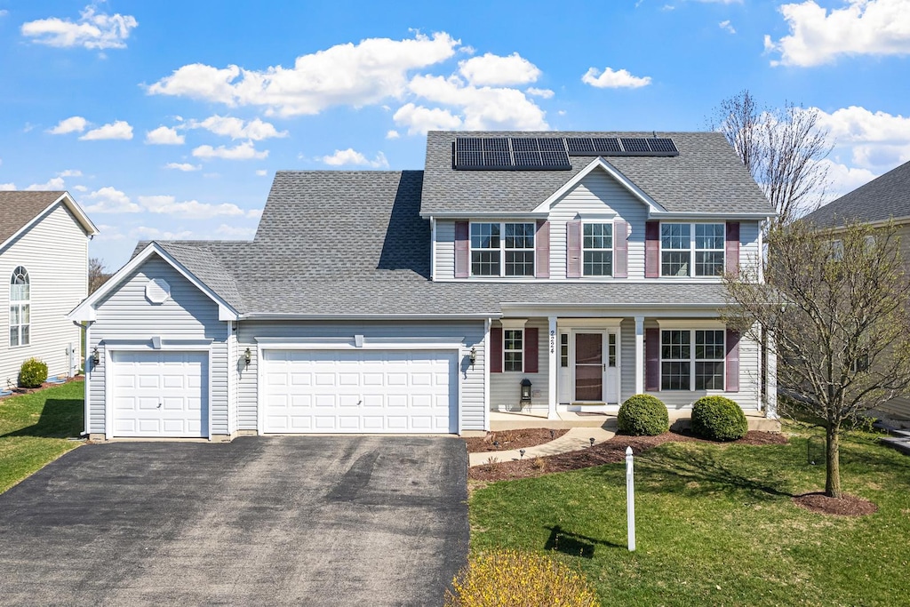 2224 James Leigh Dr, Aurora, IL 60503 - traditional-style house with a garage, aphalt driveway, a front lawn, solar panels, and a porch