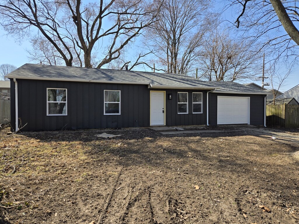 single story home featuring a garage, board and batten siding, and fence