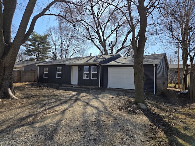 ranch-style home with dirt driveway, an attached garage, and fence