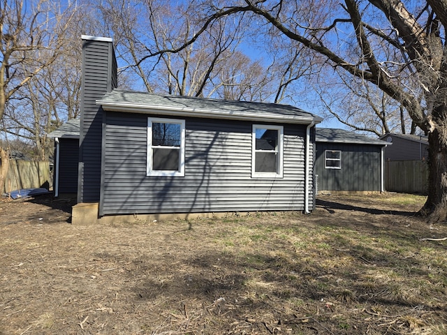 view of side of home with a chimney and fence