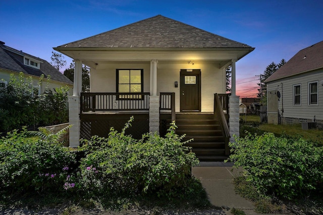 view of front of property featuring a porch, central AC, and roof with shingles