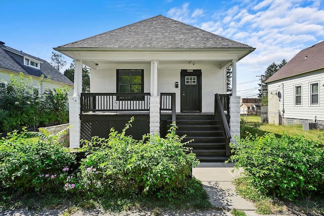 view of front of home with a porch, cooling unit, and a shingled roof