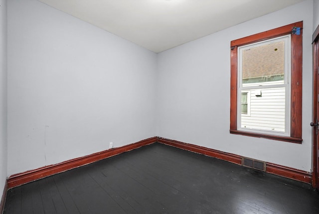 empty room featuring visible vents, baseboards, and hardwood / wood-style flooring