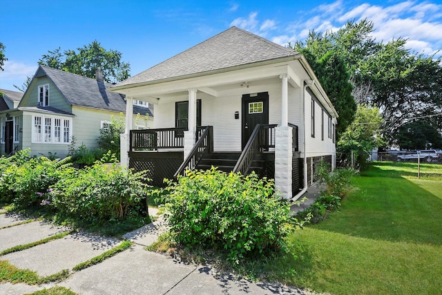 view of front of house with fence, a porch, a front lawn, and a shingled roof