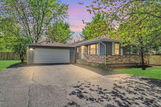 117 Arthur Ave, South Elgin, IL 60177 - view of front facade featuring fence, stone siding, a garage, and an outbuilding