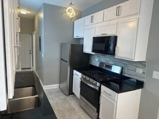 5208 S Paulina St, Chicago, IL 60609 - kitchen with dark countertops, white cabinetry, stainless steel appliances, and tasteful backsplash