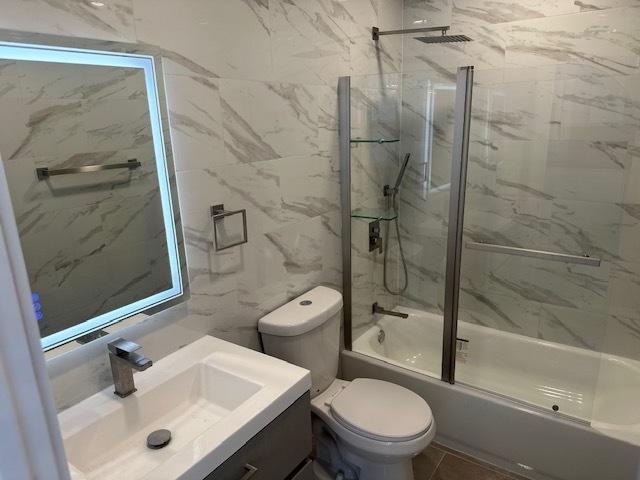 5208 S Paulina St, Chicago, IL 60609 - bathroom featuring enclosed tub / shower combo, toilet, vanity, and tile walls