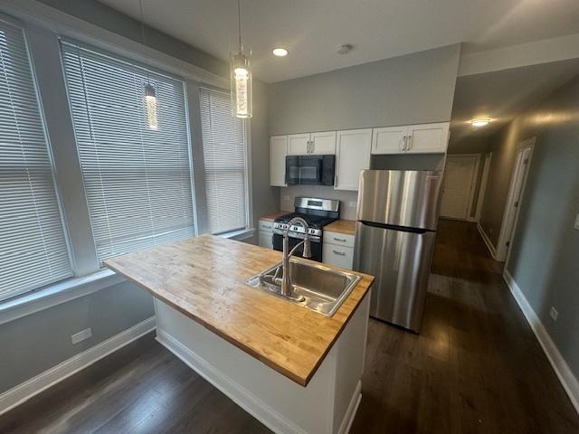 5208 S Paulina St, Chicago, IL 60609 - kitchen with a sink, baseboards, white cabinetry, and stainless steel appliances