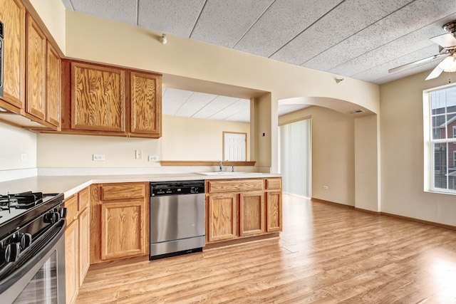 kitchen with light countertops, arched walkways, gas range oven, and dishwasher