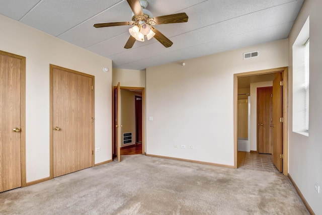 unfurnished bedroom featuring visible vents, a ceiling fan, baseboards, and light colored carpet