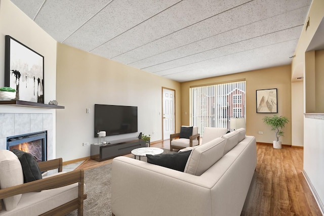 living area featuring baseboards, wood finished floors, and a tile fireplace