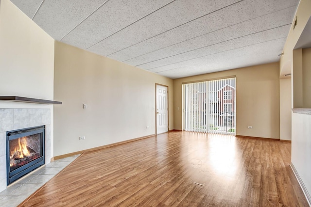 unfurnished living room with baseboards, wood finished floors, and a fireplace