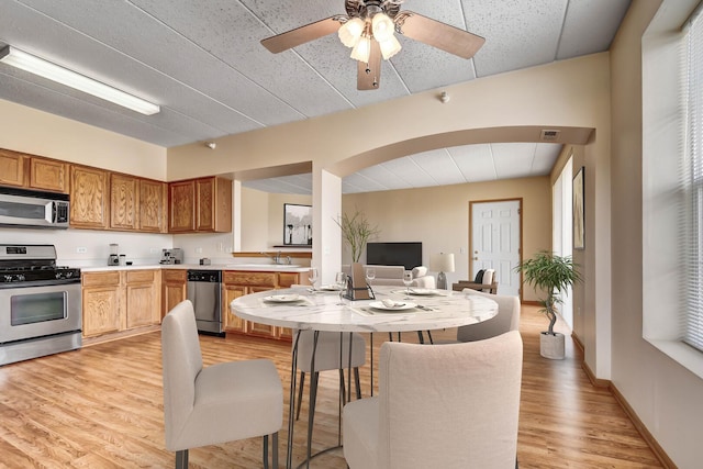 kitchen featuring a sink, light countertops, a ceiling fan, light wood finished floors, and appliances with stainless steel finishes
