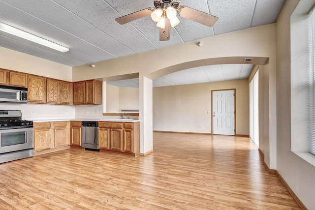 kitchen with light countertops, appliances with stainless steel finishes, ceiling fan, and light wood-style flooring