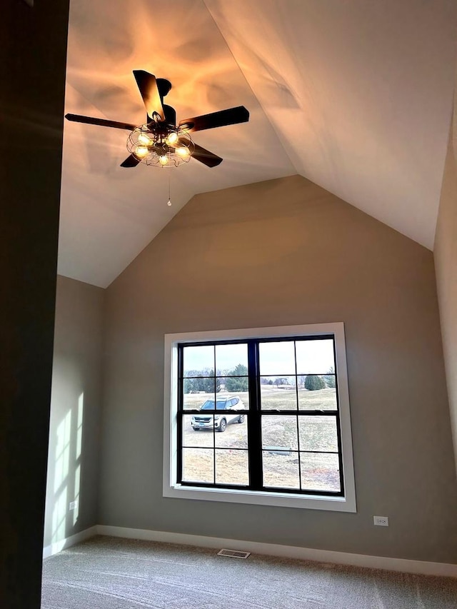 carpeted spare room featuring visible vents, baseboards, a ceiling fan, and vaulted ceiling