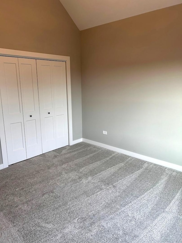 unfurnished bedroom with lofted ceiling, a closet, baseboards, and carpet floors