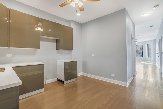 kitchen featuring modern cabinets, a ceiling fan, baseboards, and light wood finished floors