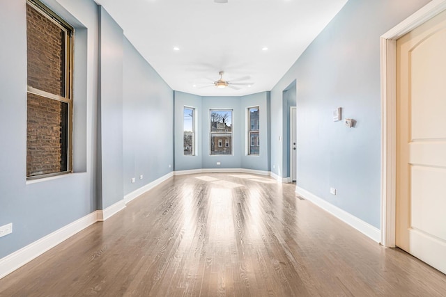 unfurnished room featuring baseboards, wood finished floors, and ceiling fan