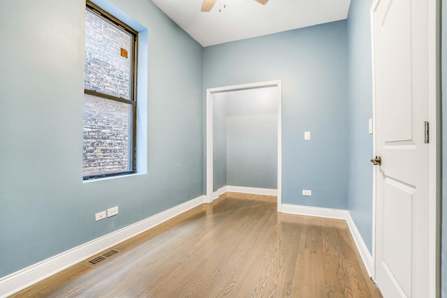 empty room with wood finished floors, a healthy amount of sunlight, visible vents, and ceiling fan
