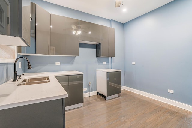kitchen featuring a sink, light wood-type flooring, ceiling fan, and gray cabinets