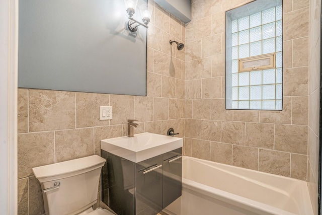 bathroom with vanity, tile walls, toilet, and shower / bathtub combination