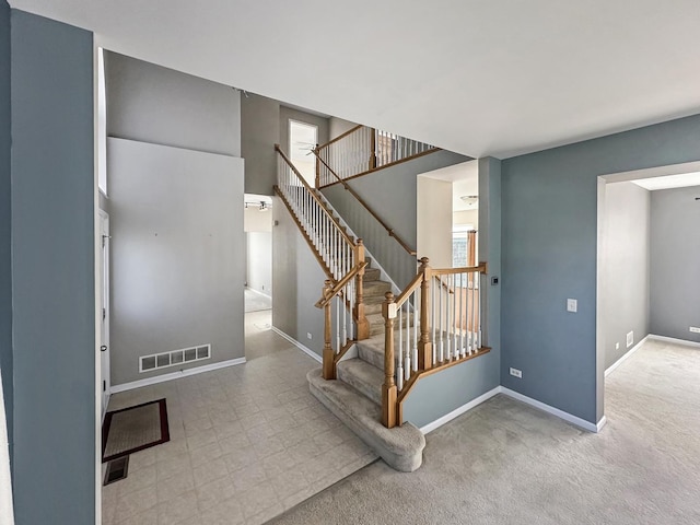 stairway featuring baseboards and visible vents