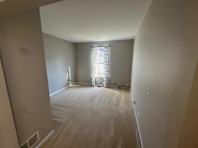 empty room featuring baseboards, carpet floors, and visible vents