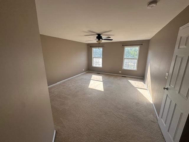 spare room featuring a ceiling fan, carpet, and baseboards