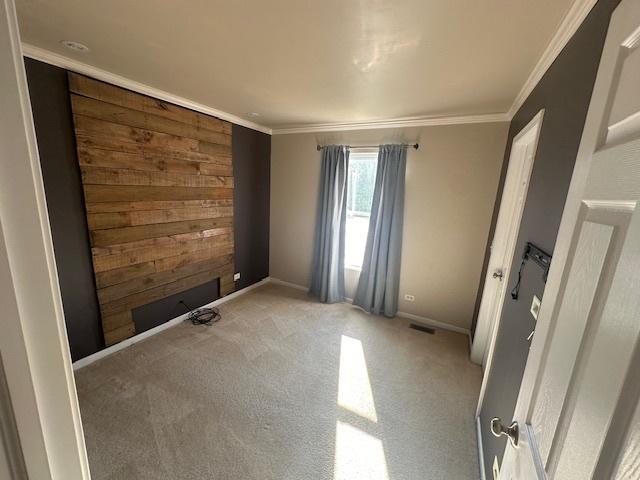 unfurnished room with visible vents, light colored carpet, crown molding, and baseboards