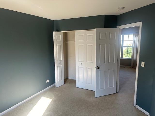 unfurnished bedroom with light carpet, baseboards, and a closet