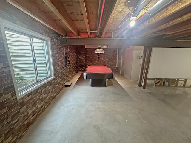 below grade area featuring billiards, plenty of natural light, and brick wall