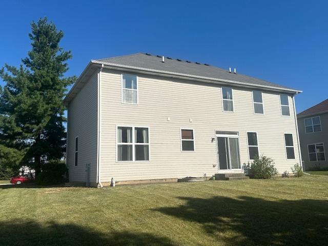 rear view of house featuring a lawn and entry steps